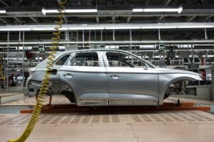 Car manufacturing plant illustrating supply chain impact relevant to best forex prop trading firms